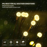 Four Siuholi solar firefly starburst stake lights with warm white LEDs glowing in a garden at night - view 6