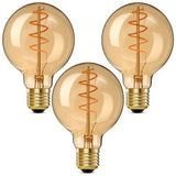 Three G25 amber glass spiral LED Edison bulbs with E26 base standing upright, warm 2000K vintage glow
