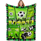 Green flannel throw blanket 60x80 inches with all-over soccer ball print, folded on a sofa, soft anti-pill fabric
