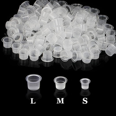 300 clear disposable plastic tattoo ink cups in small, medium, and large sizes arranged together, Urknall brand pigment caps