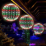 Two 16-inch multicolor LED Christmas ball sphere lights with stainless steel frame glowing outdoors in a yard at night - view 4
