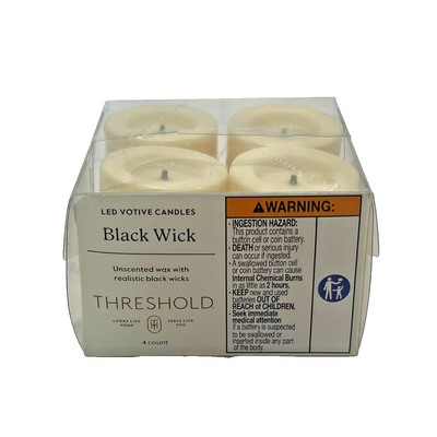 Four cream LED flameless votive candles with black wicks arranged together, Threshold brand battery-operated unscented decor set
