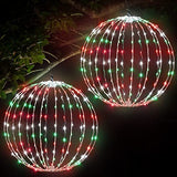 Two 16-inch multicolor LED Christmas ball sphere lights with stainless steel frame glowing outdoors in a yard at night - view 2