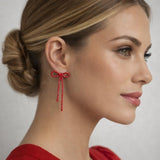 Silver bow-shaped clip-on dangle earrings with round clear CZ rhinestones on white background - view 3