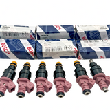 Set of 6 Bosch OEM cross-reference 0280150440 fuel injectors in mixed condition, including 4 new units, laid on surface