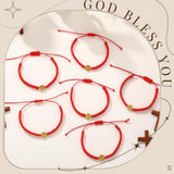 Set of 20 red and gold cord Saint Benedict medal bracelets with S-hook clasp displayed on a flat surface - view 6