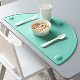 Teal oval silicone placemat 20x11 inches with raised edges and suction cups on a dining table surface - view 2