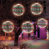 Two 16-inch multicolor LED Christmas ball sphere lights with stainless steel frame glowing outdoors in a yard at night - view 3