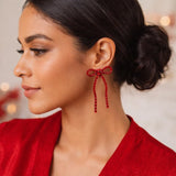 Silver bow-shaped clip-on dangle earrings with round clear CZ rhinestones on white background - view 2