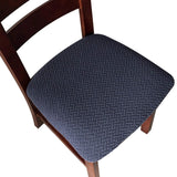 Four navy blue jacquard stretch dining chair seat covers with anti-slip straps laid flat and fitted on chairs