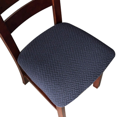 Four navy blue jacquard stretch dining chair seat covers with anti-slip straps laid flat and fitted on chairs