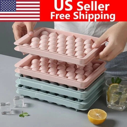 Five pink and blue round ice ball maker trays with lids stacked together, showing sphere mold cavities for whiskey cocktails
