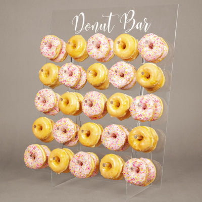 Clear acrylic donut wall display stand 26x22 inches with 25 pegs holding donuts for wedding party decor by Opal Lily
