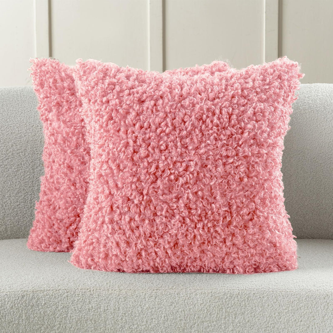 Two pink faux wool boucle throw pillow covers 22x22 inches with gold heart charm zipper on a modern couch