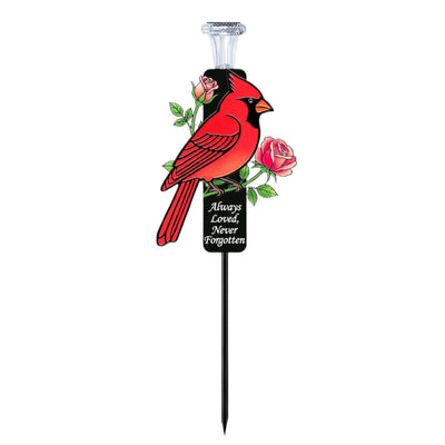 Solar-powered red cardinal metal garden stake with warm white LED light glowing, designed as a memorial grave marker for outdoor use