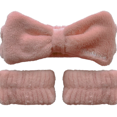 Biodance pink fluffy plush spa headband and two wristbands laid flat, elastic bow-style skincare accessory set