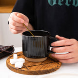 Set of 4 stackable black textured ceramic coffee mugs 12oz arranged in a stack on a white surface - view 4