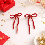 Silver bow-shaped clip-on dangle earrings with round clear CZ rhinestones on white background - view 5