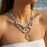 IQIC two-layer boho beaded necklace with cowrie shell and starfish charms, blue beads and gold-tone accents on white background - view 3