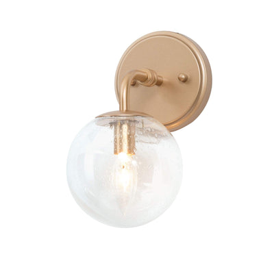 Gold metal wall sconce with handblown seeded globe glass shade 5.5 inch diameter mounted on wall, warm ambient light