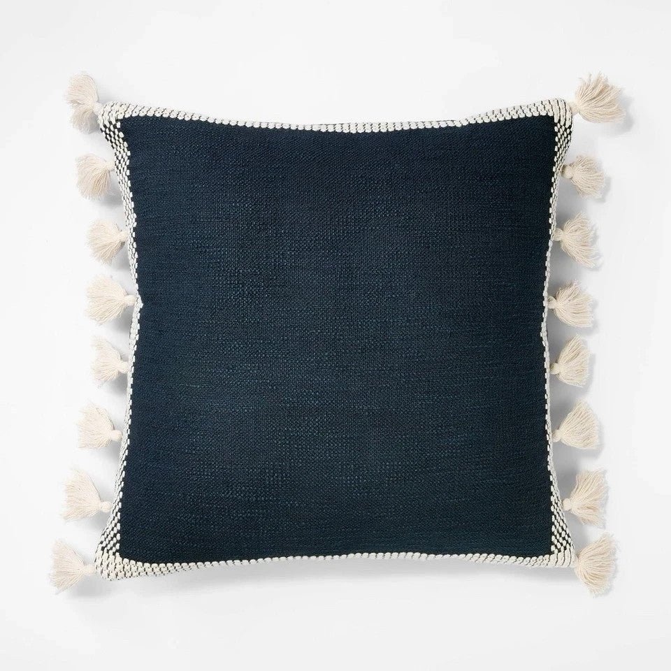 Threshold Studio McGee 20x20 inch navy blue throw pillow with cream woven border and side tassels on sofa