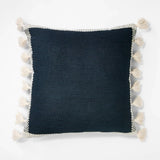 Threshold Studio McGee 20x20 inch navy blue throw pillow with cream woven border and side tassels on sofa