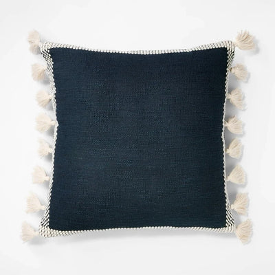 Threshold Studio McGee 20x20 inch navy blue throw pillow with cream woven border and side tassels on sofa