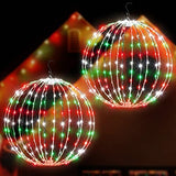 Two 16-inch multicolor LED Christmas ball sphere lights with stainless steel frame glowing outdoors in a yard at night